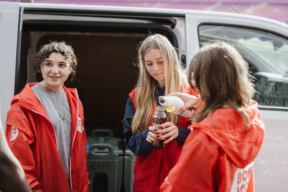 Un groupe de bénévoles remplissant une gourde de café d'une personne à la rue