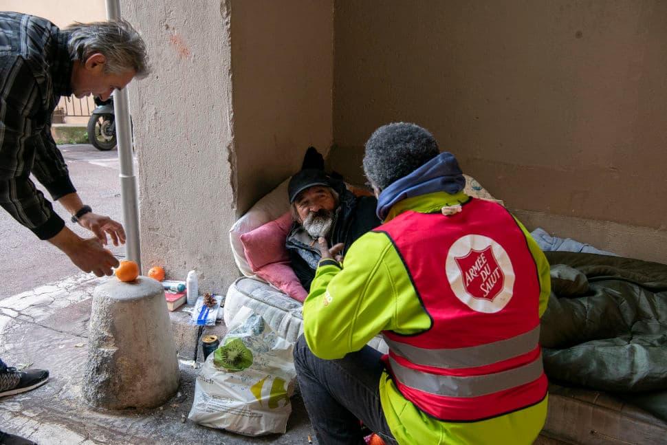 Un bénévole de l'Armée du Salut auprès d'une personne qui dort dehors