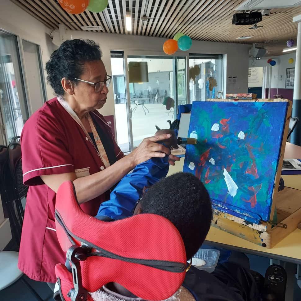 Iris Dossimont, monitrice-éducatrice à la MAS de Montfermeil vient en aide aux artistes peintres, résidents de l'établissement