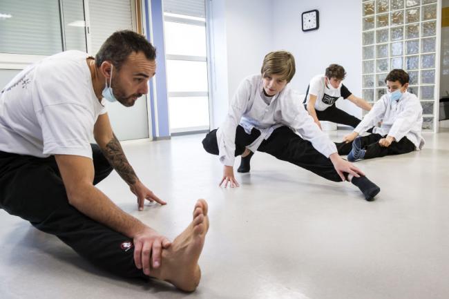 Un entraineur avec des jeunes qui font du judo