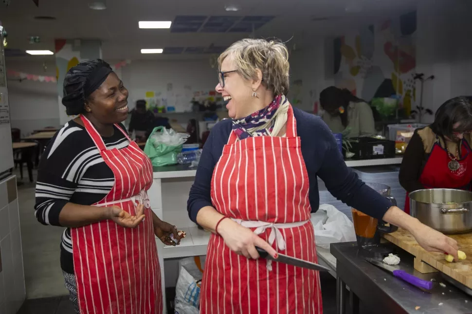 Une bénévole et une personne accueillie échangent lors d'un atelier cuisine à La Cocotte de l'Armée du Salut à Paris