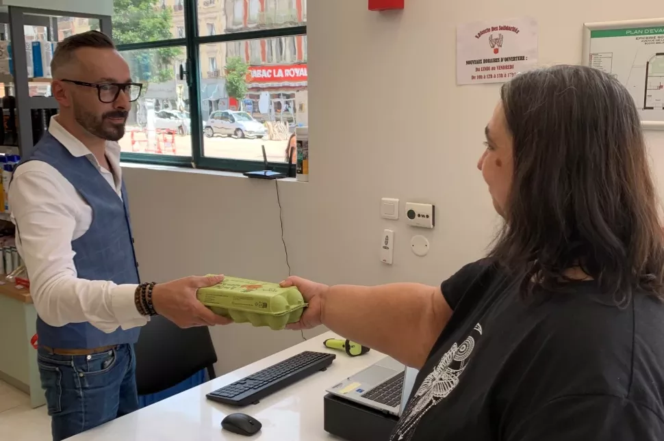 Une personne achète des oeufs à l'épicerie des solidarités de Belfort